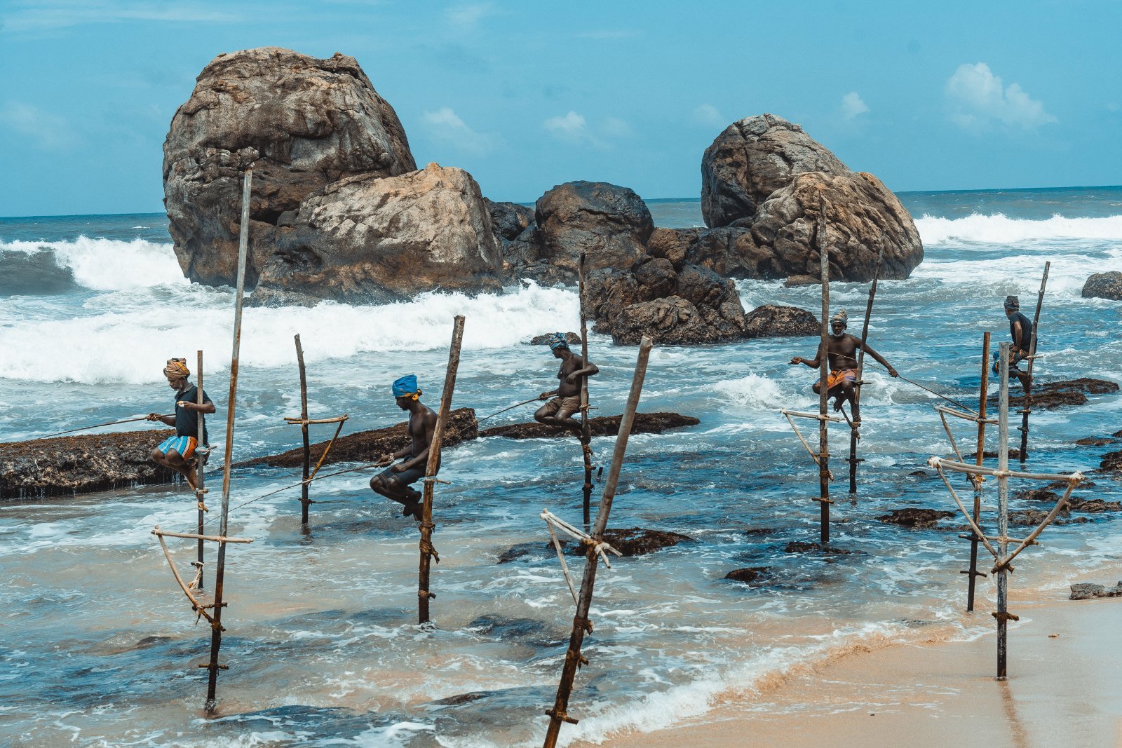 Fisherman balancing on wooden stilts in the ocean waves, capturing traditional fishing methods.