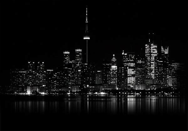 Toronto city skyline at night with illuminated skyscrapers and CN Tower.